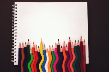Okul defteri. Gökkuşağı renkli kalemler yan yana sallanıyor