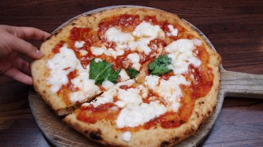 Tahta pizza kabuğundan alınmış bir dilim pizza.