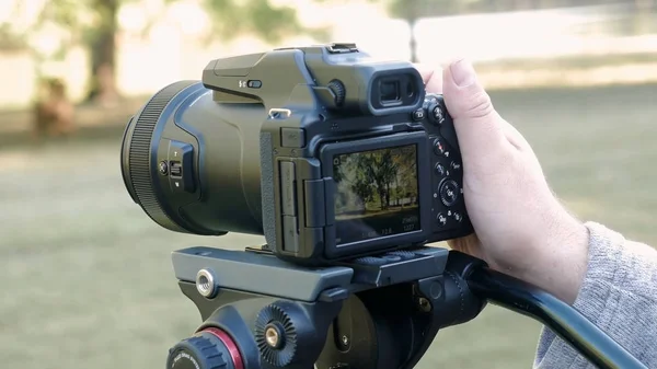 Eller dijital kamerayı tutuyor ve arka planda fotoğraf ve video çekimi yapıyor. Manzara doğası, doğa gezisi fotoğrafçılığı.