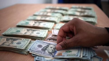 Siyah adamın eli, tahta masanın üzerinde banknotları ve yığınla parayı sayıyor. konsept işi ve mali.