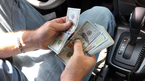 Man`s hands with dollars in a car. Man counting money