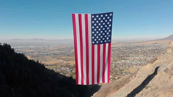 American flag hanging vertically against blue sky outdoor. Nature background