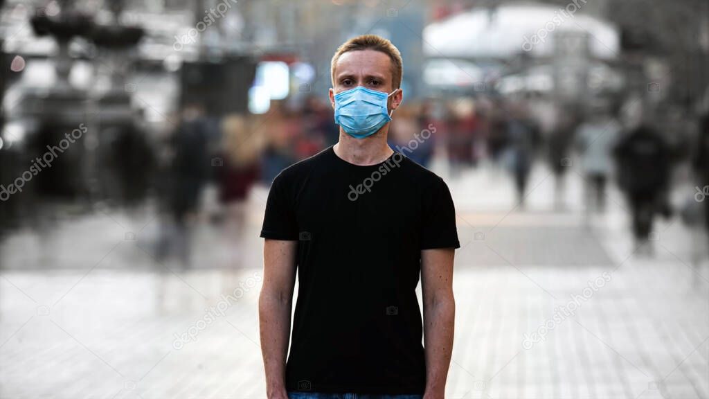 Young man wearing a face mask in city street outdoor as protection against an airborne virus, bacteria, coronavirus.
