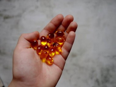 Elinde balık yağı-omega-3 dolu sarı jelatin kapsüllerin tasarımı.