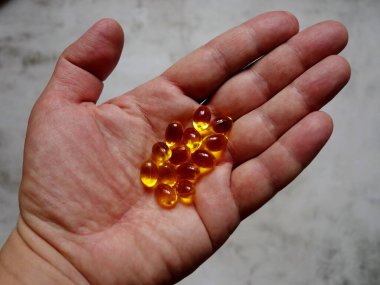 Elinde balık yağı-omega-3 dolu sarı jelatin kapsüllerin tasarımı.