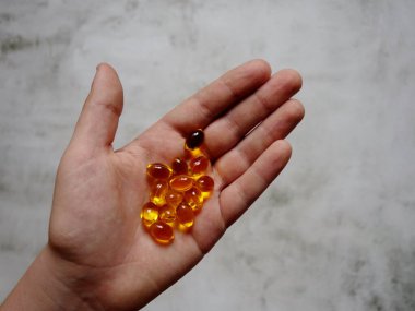 Elinde balık yağı-omega-3 dolu sarı jelatin kapsüllerin tasarımı.