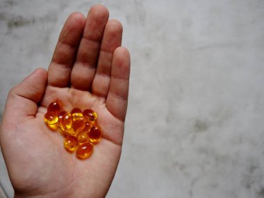 Elinde balık yağı-omega-3 dolu sarı jelatin kapsüllerin tasarımı.