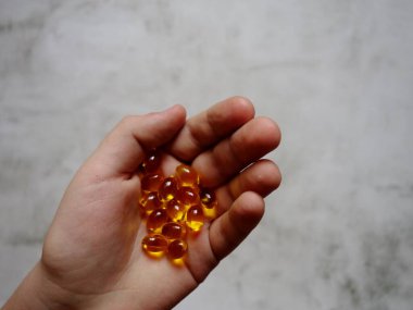 Elinde balık yağı-omega-3 dolu sarı jelatin kapsüllerin tasarımı.