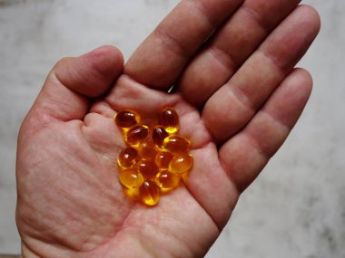Elinde balık yağı-omega-3 dolu sarı jelatin kapsüllerin tasarımı.