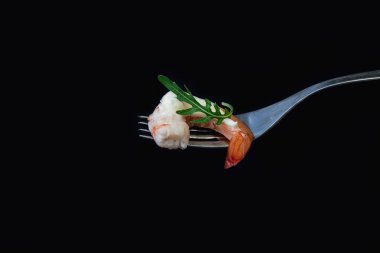 Siyah arka planda krema soslu çatallı karides.