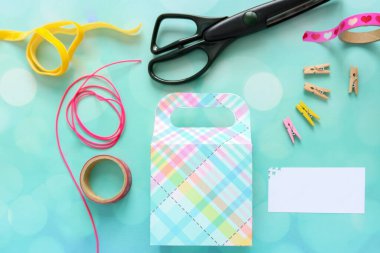 Mavi arka planlı el yapımı hediye kutusu ve süslemek için bir sürü malzeme.