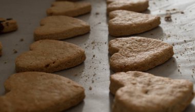 Pişirme kağıdında kalp şeklinde kurabiyeler.