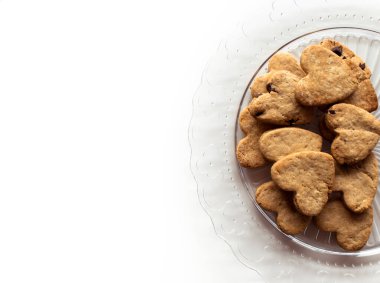 Beyaz bir masada şeffaf bir tabakta bir sürü kalp şeklinde kurabiye.