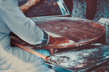 Türk ulusal yemeği - etli ekmek. Beyazlı Türk kadın dolgulu düz kek pişiriyor. Çok lezzetli yemekler..