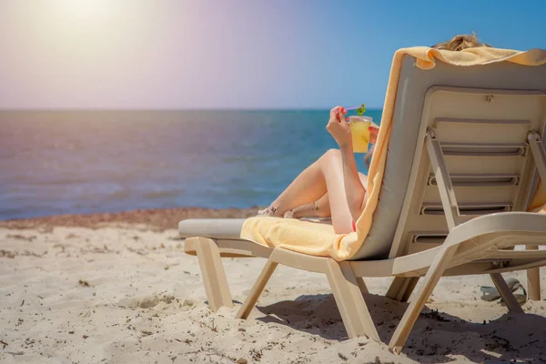 女人躺在海边豪华旅馆的日光浴床上 享受暑假 手里拿着一杯鸡尾酒 — 图库照片