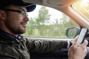 Araba kullanırken cep telefonu kullanan bir adam. İç görünüm.