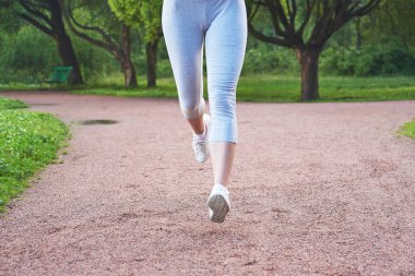 Parkta koşu eğitimi almış genç bir kız. Kameraya doğru gidiyor..