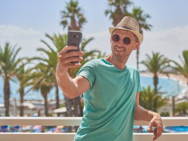 Güneş şapkalı adam güzel deniz manzarasına karşı selfie çekiyor. Santa Susanna 'da. Kataluna. İspanya.