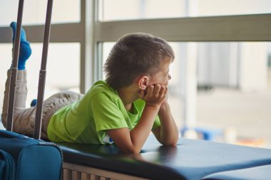 Beyaz çocuk havaalanında uçağa binmek için bekliyor..