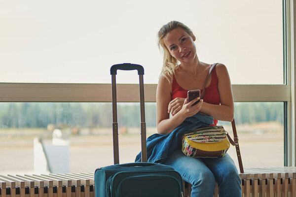 Молодая красивая женщина с помощью мобильного телефона во время ожидания посадки в аэропорту
. 