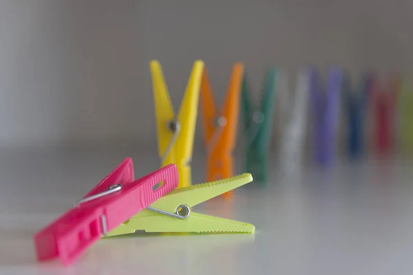 İki renkli plastik mandal yan yana kıvrımlı bir çizgide sıralanmış - pembe, yeşil, sarı, turuncu, mor, beyaz
