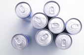 Neotevřené plechovky od nápojů shora shlížející na hliníková víčka na bílém pozadí