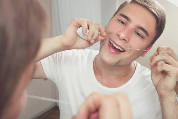 Человек чистит зубы зубной нитью — стоковое фото