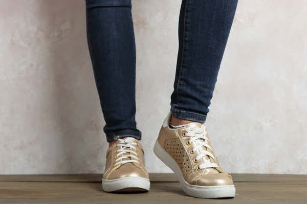 Kvinnliga ben i guld sneakers — Stockfoto