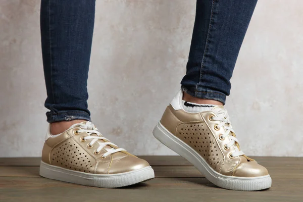 Kvinnliga ben i guld sneakers — Stockfoto