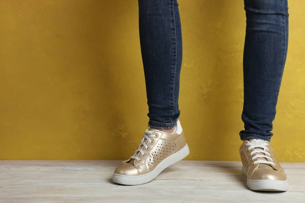 Kvinnliga fötter i gyllene sneakers — Stockfoto