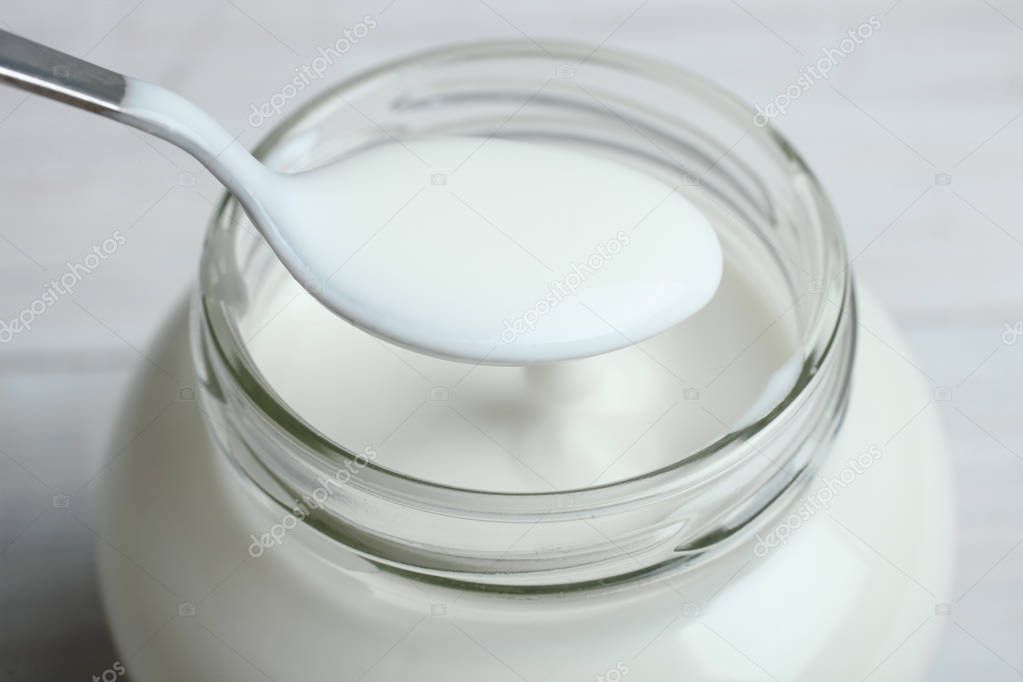 A jar with a yogurt and a spoon 