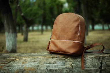  bir ahşap bank üzerinde kahverengi sırt çantası 
