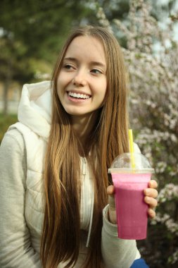 Bir kız pembe smoothies içiyor
