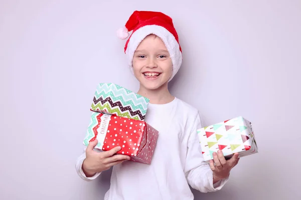 Chłopiec w kapeluszu Mikołaja z prezentami — Zdjęcie stockowe