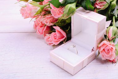 Pembe güller, pembe arka planda hediye kutusunda bir yüzük..