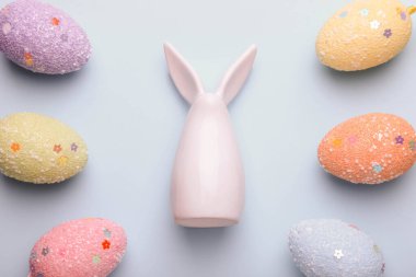 Seramik Paskalya tavşanı ve mavi arka planda dekoratif renkli yumurtalar..