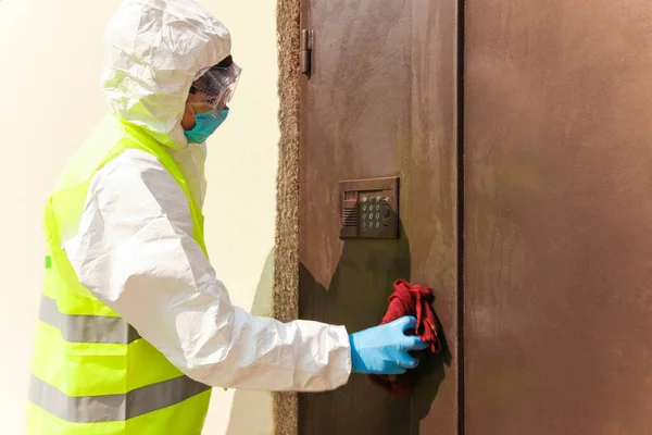 A specialist in a protective suit disinfects the entrance to the house. Epidemic control.
