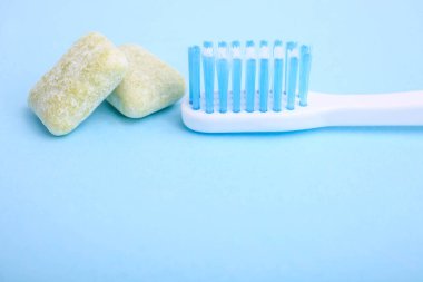 Diş fırçası ve mavi bir arka planda çok renkli sakız..