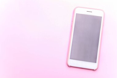 Hassas pembe arka planda modern beyaz akıllı telefon..