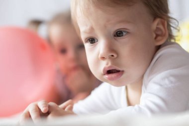 Küçük çocuklar karın üstü uzanıp çizgi film seyrediyorlar. Güzel bebekler renkli balonların arasında yatar. Küçük kız ve erkek kardeş birlikte çizgi film izliyorlar.