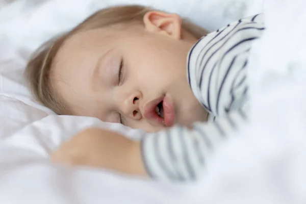 Lille blond baby sover i sin seng - Stock-foto