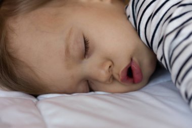 Küçük sarışın bebek onun yatağında uyuyor.