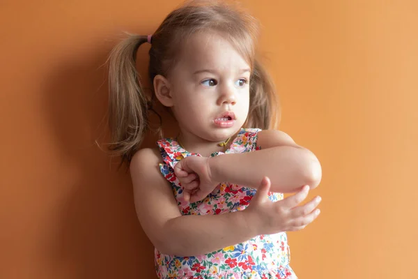 Portret van een mooi meisje van twee jaar op een oranje achtergrond. Emoties van een jong kind — Stockfoto