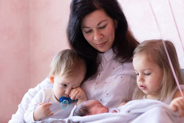 Primeiro encontro entre uma irmã, irmão e um bebê recém-nascido em casa — Fotografia de Stock