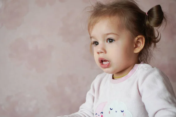 A little girl of Slavic appearance dressed in pink pajamas stands in a cradle. A sleepy child, three years old, stands in the cot Stock Image