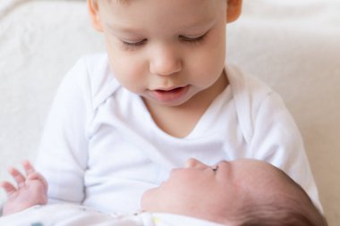 Ağabeyi ve yeni doğmuş kız kardeşi. Ağabeyi yeni doğan bebekle oynuyor..