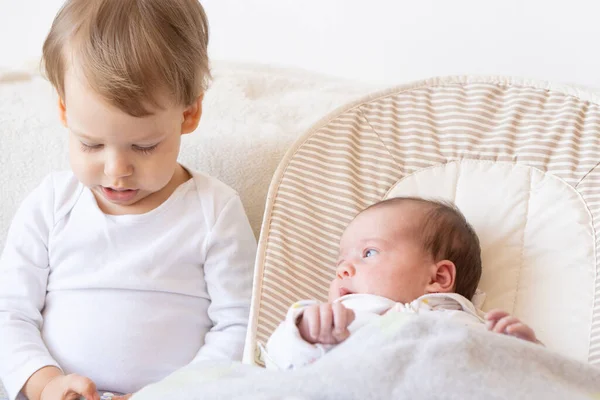 Older brother with newborn sister. The brother plays with the newborn. — Stock Photo, Image