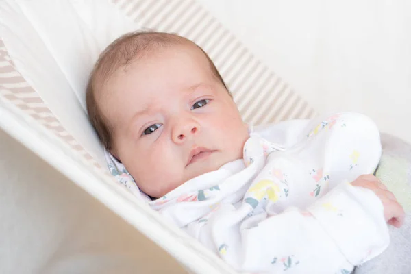 Bebê recém-nascido encontra-se em cadeira de balanço dentro de casa — Fotografia de Stock