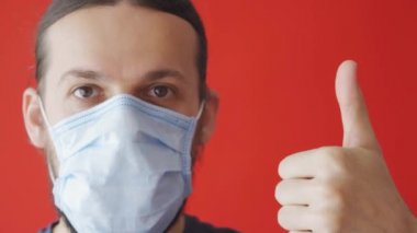 Kırmızı arka planda tıbbi maske takan hasta bir adamın portresi. Coronavirus konsepti. Sağlığınızı koruyun.