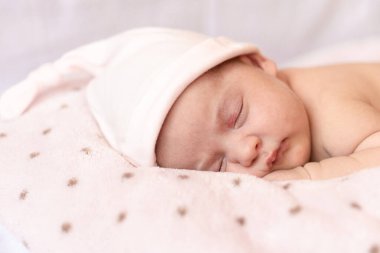 Sevimli yeni doğmuş bebek yumuşak bir battaniyede karnının üstünde uyuyor. Şapkalı yeni doğmuş bir bebek yumuşak bir battaniyenin üzerinde uyur.